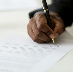 Close up of black worker signing legal documentation Return Policy - Hats From OZ UK